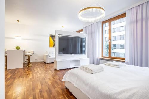 a white bedroom with a large television on a bed at Luxury Princessa Apartment & garage & cable tv channels in Warsaw