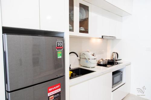 a kitchen with a stainless steel refrigerator and white cabinets at Central Westlake Residence 2 - By Pegasy Group in Hanoi
