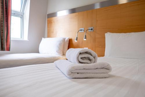 a hotel room with two beds with towels on the bed at Maiden Oval in London