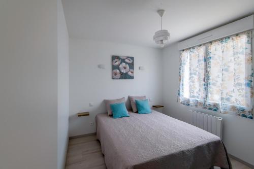 une chambre avec un lit avec des oreillers bleus et une fenêtre dans l'établissement Logis de la Perruche - Maison avec terrasses, à Montreuil-Bellay
