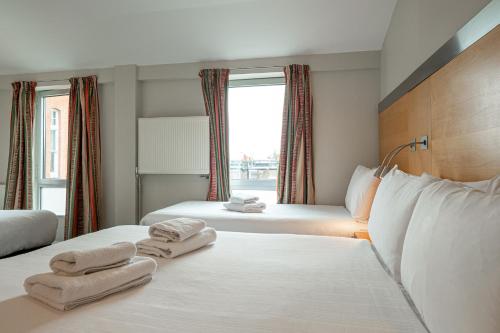 a hotel room with two beds with towels on them at Maiden Oval in London