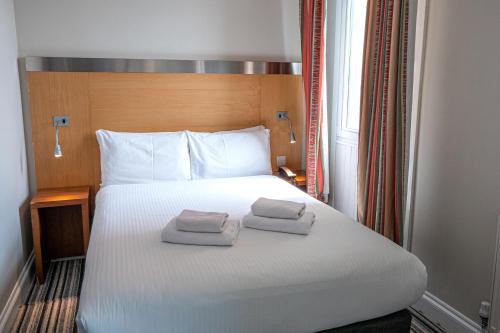 a hotel room with a bed with two towels on it at Maiden Oval in London