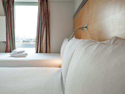 duas camas num quarto de hotel com almofadas brancas em Maiden Oval em Londres