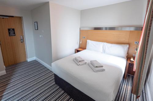 a hotel room with a bed with two towels on it at Maiden Oval in London