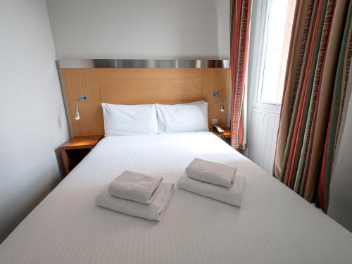 a bedroom with a bed with two towels on it at Maiden Oval in London