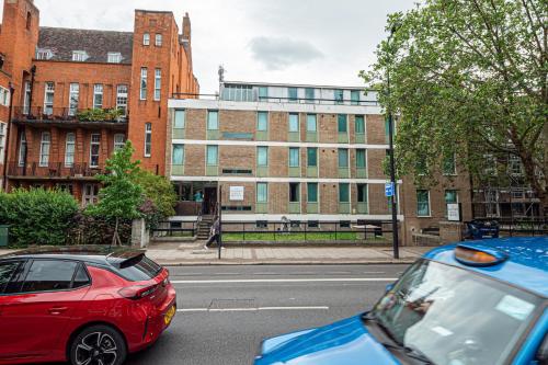 two cars parked on a street in front of a building at Maiden Oval in London