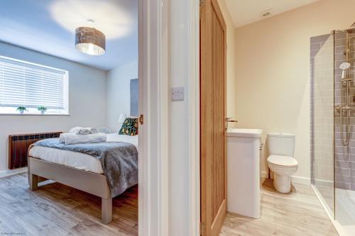 a bedroom with a bed and a bathroom with a toilet at Romney Barn in Minster Lovell