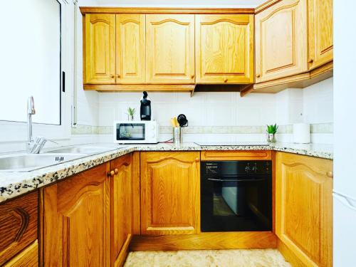 cocina con armarios de madera y lavavajillas negro en Oyansa Apartments en Vilanova i la Geltrú