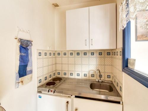 une petite cuisine avec des armoires blanches et un évier dans l'établissement Duplex cosy pour 5 pers., balcon sud, parking, proche centre et remontées, navette hivernale - FR-1-401-82, à Cauterets