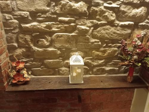 a lantern sitting on a table in front of a stone wall at B&B La Rocchetta dal Sròz in Le Serucce