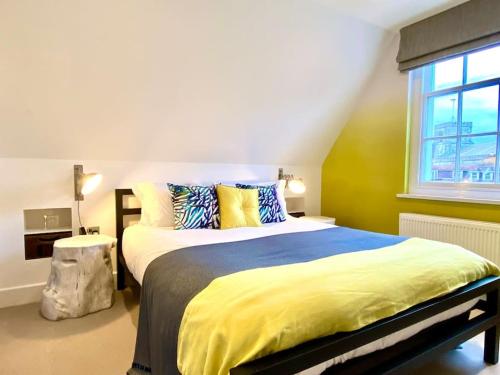 um quarto com uma cama grande com lençóis amarelos e uma janela em Stunning Little House on Poole Quay - Free Secure Parking & WiFi - in the heart of the Old Town - Great Location - Free Parking - Fast WiFi - Smart TV - Newly decorated - sleeps 2! Close to Poole & Bournemouth & Sandbanks em Poole