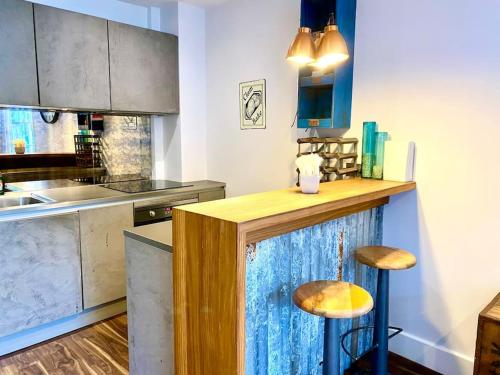 a kitchen with a counter with two stools at Stunning Little House on Poole Quay - Free Secure Parking & WiFi - in the heart of the Old Town - Great Location - Free Parking - Fast WiFi - Smart TV - Newly decorated - sleeps 2! Close to Poole & Bournemouth & Sandbanks in Poole