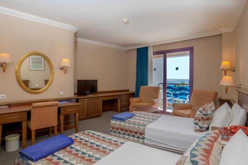 a hotel room with two beds and a mirror at Hotel Grand Kaptan - Ultra All Inclusive in Alanya
