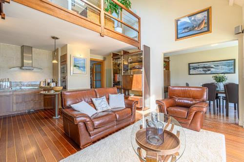 Il comprend un salon doté d'un mobilier en cuir et une cuisine. dans l'établissement Cap à Houat - Duplex de 100 m2 avec vue mer, à Sarzeau