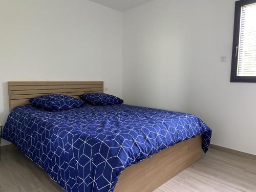- un lit avec une couette bleue et 2 oreillers dans l'établissement Appartement avec terrasse et parking privé logement C, à Ploemeur