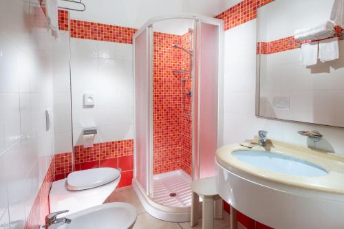 uma casa de banho com um chuveiro, um lavatório e um WC. em Hotel Odeon em Cervia