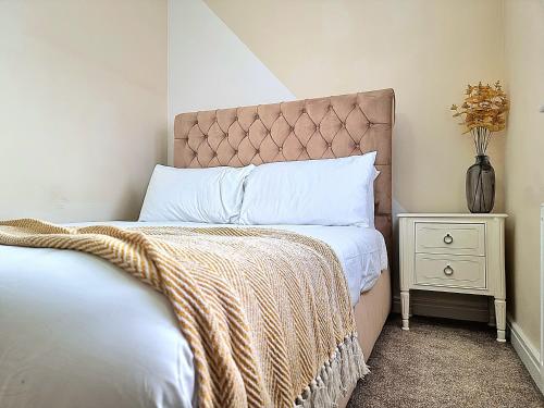 Un dormitorio con una cama y un jarrón en una mesita de noche en Detached House with Free Parking Long Stay Discounts, en Thurcaston