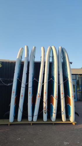 a row of surfboards lined up in a rack at MOBILHEIM HERZ LAUWERSOOG - Chalet Robbengat in Lauwersoog