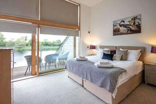 um quarto com uma cama grande e uma varanda em Waters Edge 04, Waterside Lodge P em South Cerney