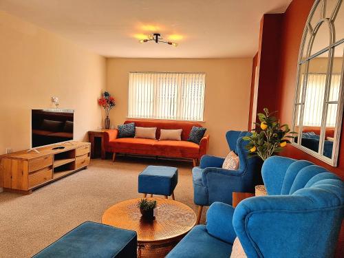 a living room with blue chairs and a tv at Detached House with Free Parking Long Stay Discounts in Thurcaston