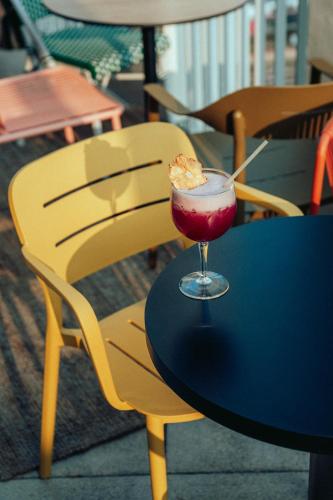 a drink sitting on a table with a yellow chair at JOST Hôtel Bordeaux Centre Gare Saint Jean in Bordeaux