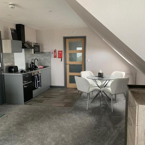 a kitchen with a table and white chairs in a room at Sunset Studio Apartments in Aberaeron