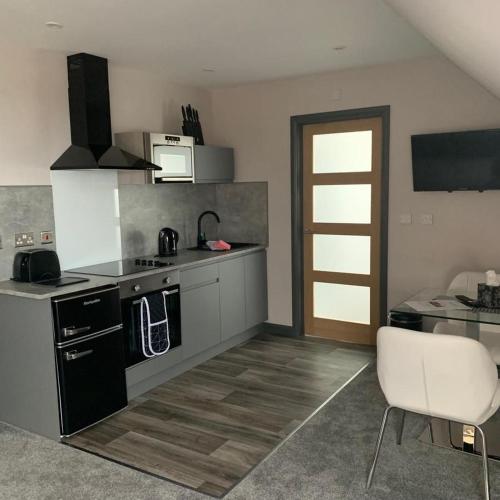 a kitchen with black and white appliances and a white chair at Sunset Studio Apartments in Aberaeron