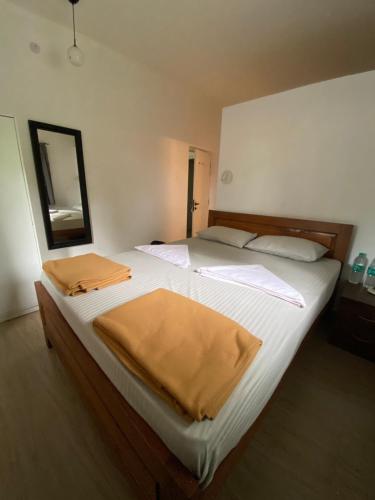 a bedroom with two beds with white sheets and a mirror at Hostel Mandala in Anjuna