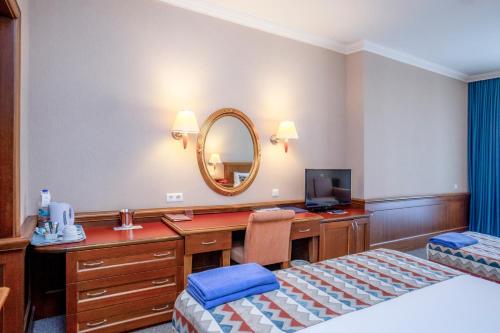 a hotel room with a bed and a desk and a mirror at Hotel Grand Kaptan - Ultra All Inclusive in Alanya