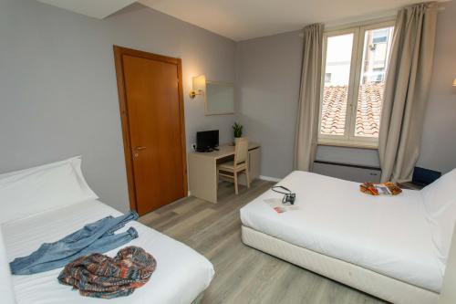 a room with two beds and a desk and a window at Hotel L'Aretino in Arezzo