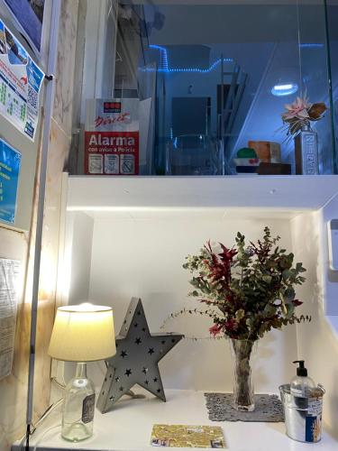 a table with a lamp and a vase of flowers on a shelf at Rincón Extremeño in Plasencia