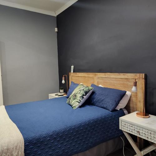 a bedroom with a blue bed with a wooden headboard at Rue Guesthouse in Postmasburg