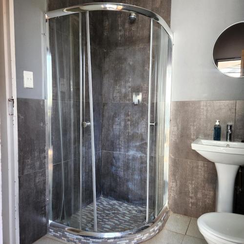 a shower with a glass door in a bathroom at Rue Guesthouse in Postmasburg