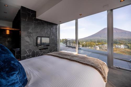 a bedroom with a large bed and a large window at The Vale Niseko in Kutchan