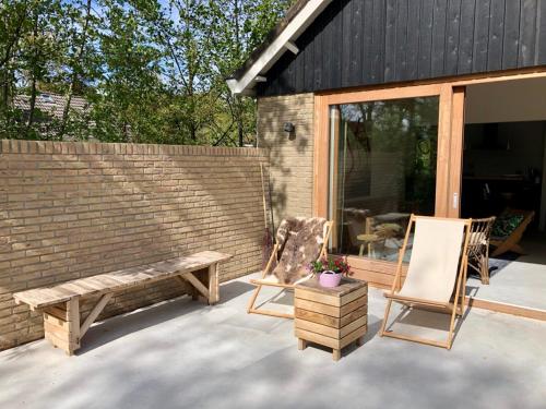 a bench and two chairs on a patio at Familiehuis Lytse Miede in Formerum