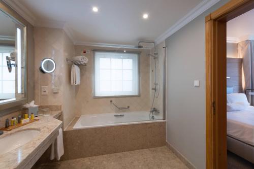 a bathroom with a tub and a sink and a bed at Praia D'El Rey Marriott Golf & Beach Resort in Casal da Lagoa Seca