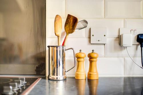 a kitchen counter with a vase with wooden utensils at GuestReady - Pacific West Coast in Rotherhithe in London