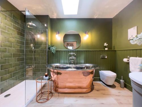 a bathroom with a copper tub in a green wall at Waters Edge, Talkin Tarn, nr Brampton in Brampton