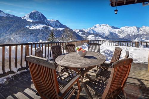 a wooden table and chairs on a deck with mountains at Chalet Morclan - OVO Network in Manigod