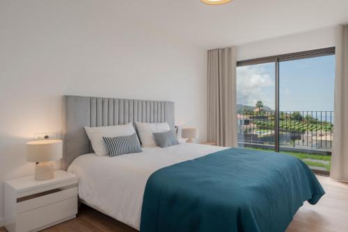 a white bedroom with a large bed and a large window at Premium villa panoramic sea-view Calheta Pearl in Estreito da Calheta