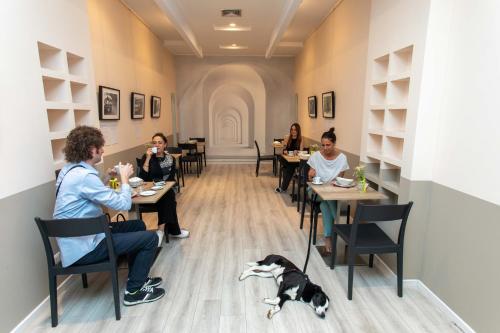 a group of people sitting at tables in a restaurant with a dog at Hotel L'Aretino in Arezzo