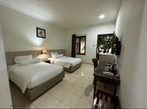 a bedroom with two beds and a desk and a television at Front One Resort Indraloka Temanggung in Temanggung