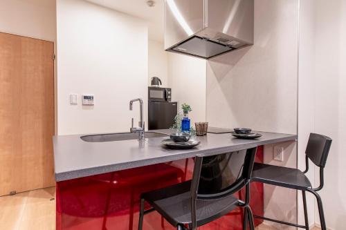 a kitchen with a counter with two chairs and a sink at Clairezione Akasaka in Tokyo