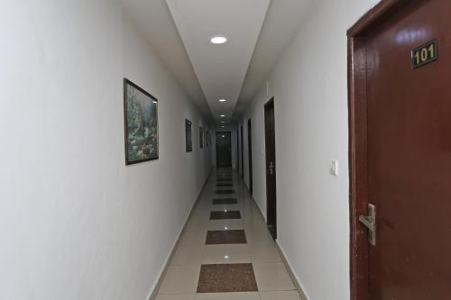 een lange hal met witte muren en tegelvloeren bij Hotel Pearl in Karnal