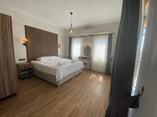 a bedroom with a white bed and a wooden floor at Tinos Otel & Bağ Evi 12 Yaş Üstü in Bozcaada