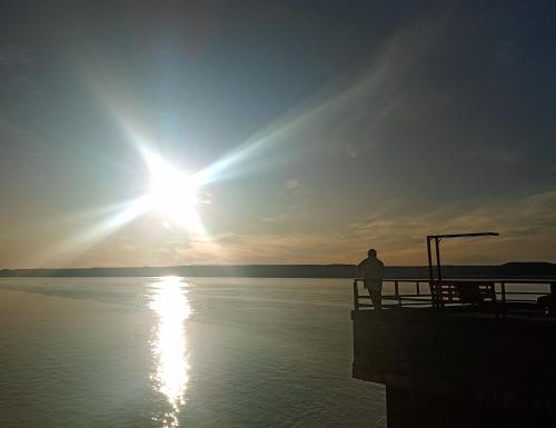 a man standing on a dock watching the sunset at 100 años ciprés in Río Gallegos