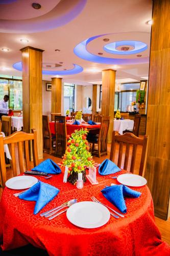 a dining room with a red table with blue napkins at Green Mountain Hotel in Arusha