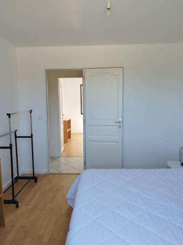 1 dormitorio con cama blanca y puerta de entrada en Maison individuelle, en Saint-Saulge