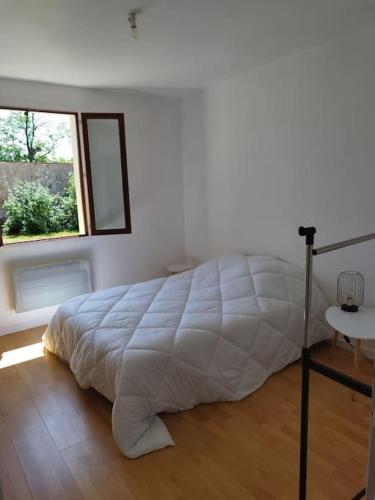 1 cama blanca en un dormitorio con ventana en Maison individuelle en Saint-Saulge