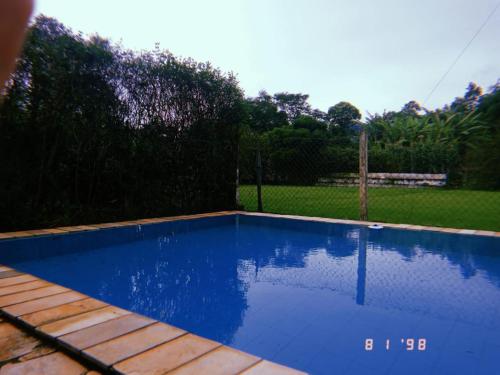 a large blue swimming pool in a yard at Pousada Nasa in São Bento do Sapucaí